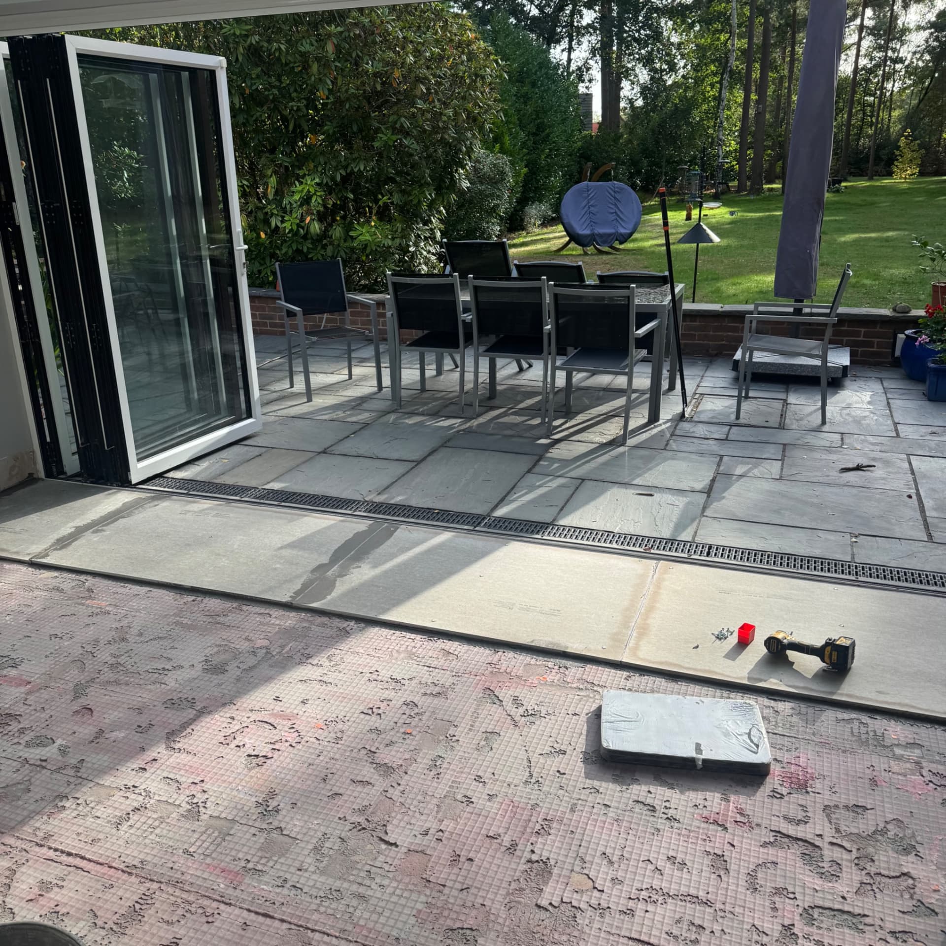 We've started laying the cement boards using S2 adhesive for extra strength, and we're screwing them down to get everything as level as possible. The boards need priming on both sides to remove the dust and ensure the adhesives and latex bond properly before we tile over them.
