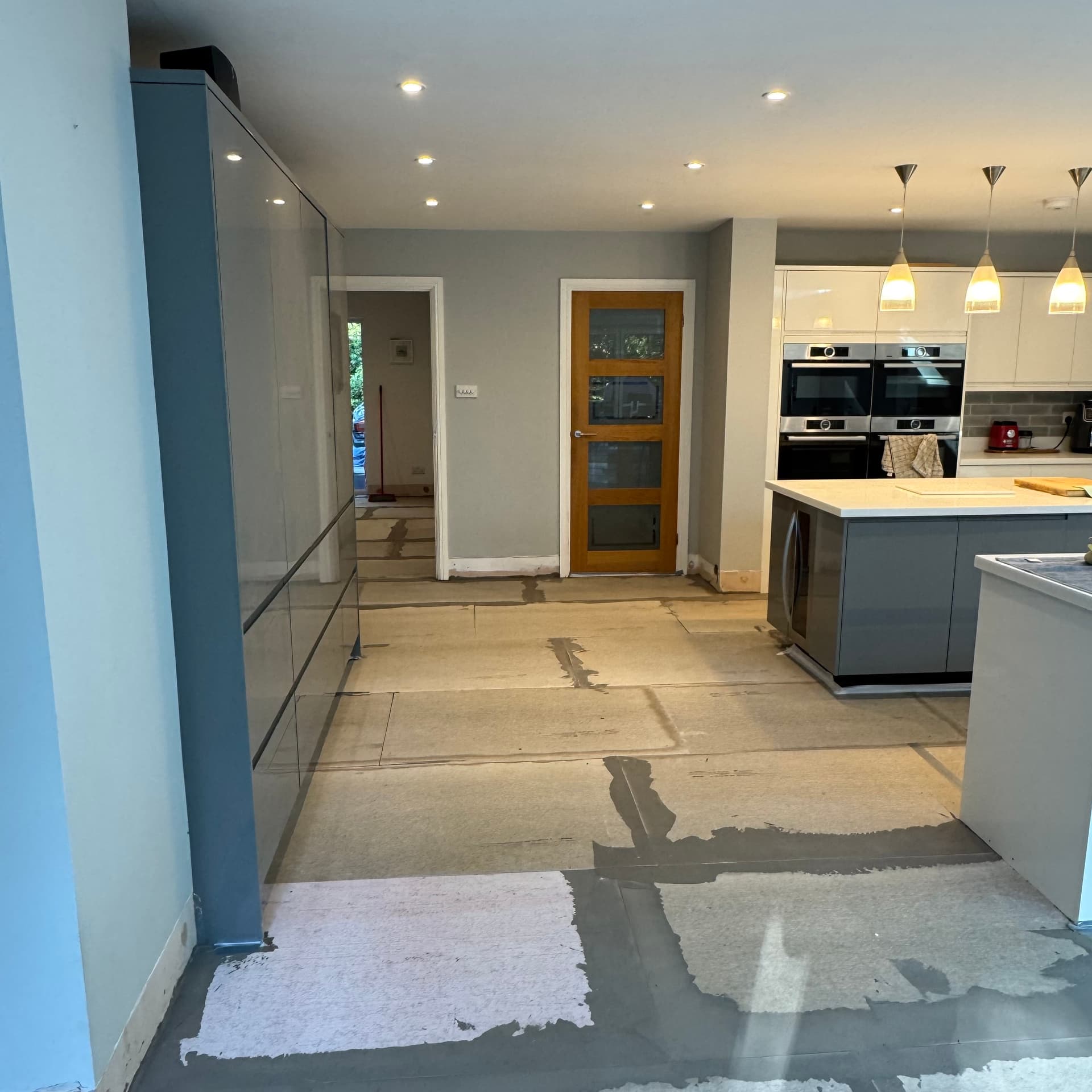 We've laid the cement boards and now we're getting ready for the self-levelling compound. You can see we've taped around the kitchen island edges and all the gaps and doorways to keep the latex flowing exactly where we need it. Next step is mixing and pouring the compound.