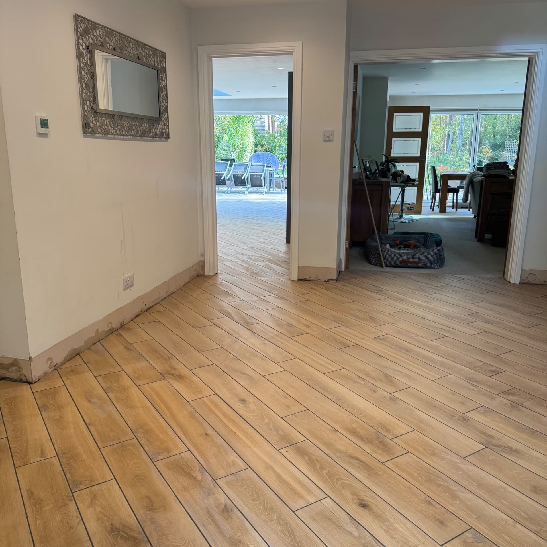 We've just washed off the grout and the hallway's looking good with the tiles running through into the kitchen. You can see the wet patches where we've cleaned up, and to the left the tiles continue into the WC as well.