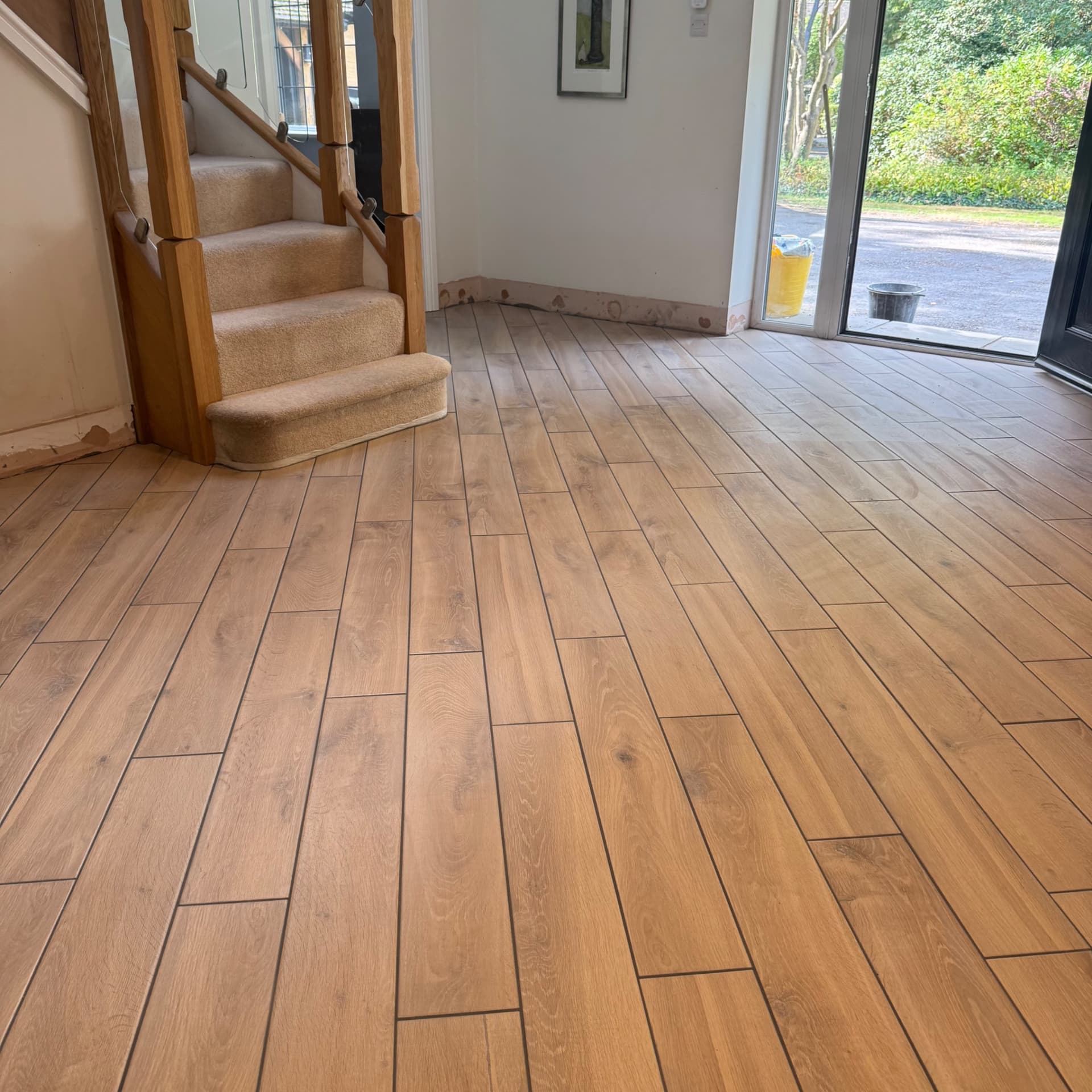 We've templated the tiles carefully around the curved step at the bottom of the staircase, and here's the finished hallway running through to the front door. The job's now complete and looking great.
