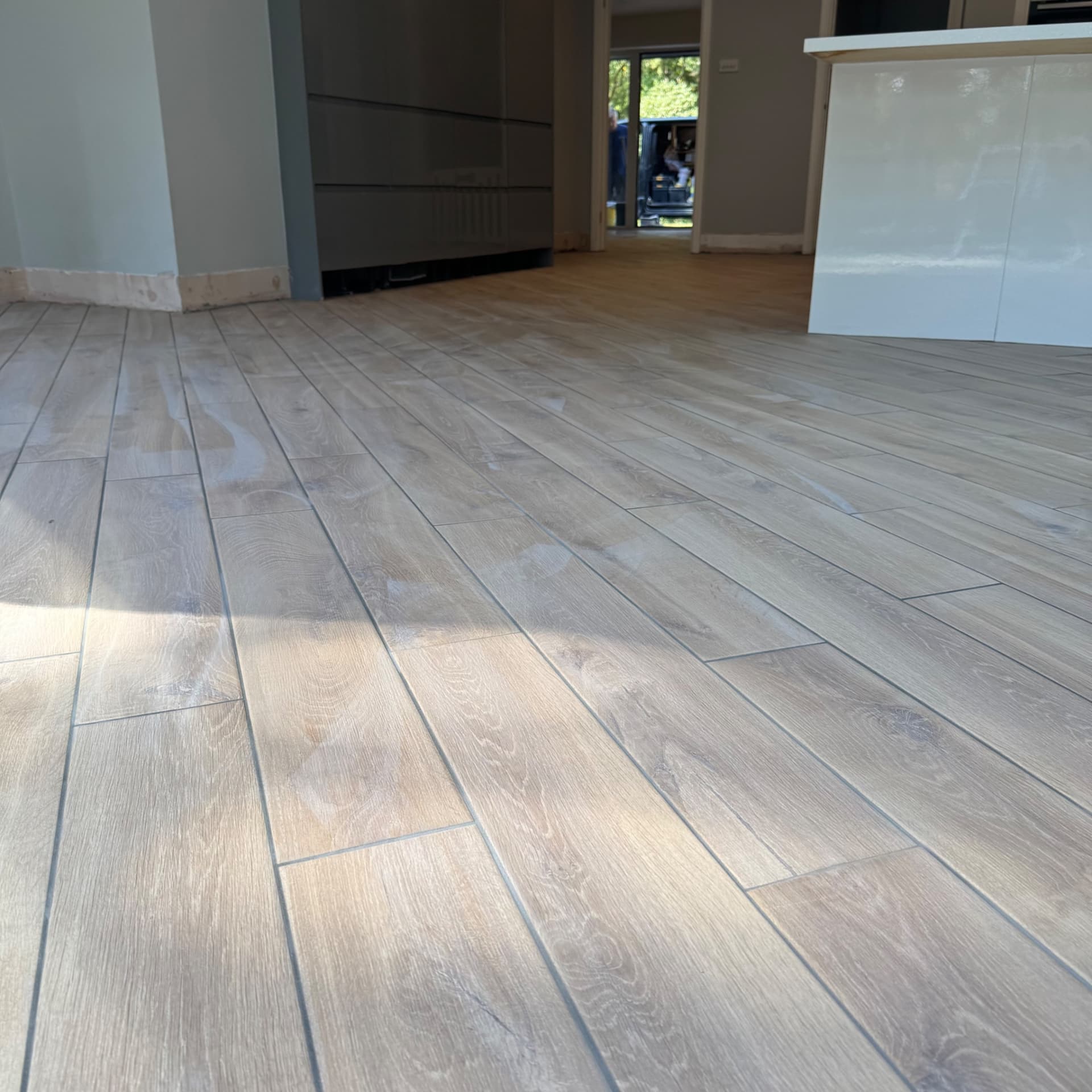 We've finished laying the kitchen floor with wood-effect tiles in a straight pattern, and they're looking great with consistent joints throughout. Just needs a final mop over to clear any smears, and then it's ready for the customer to enjoy.